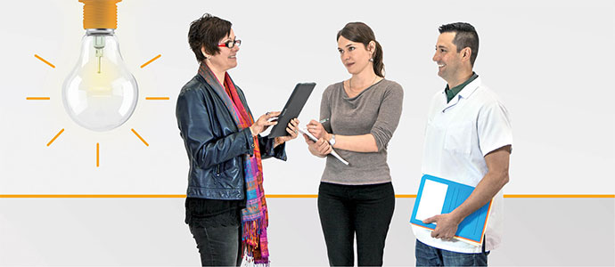 Trois professionnels discutant avec tablette et ampoule