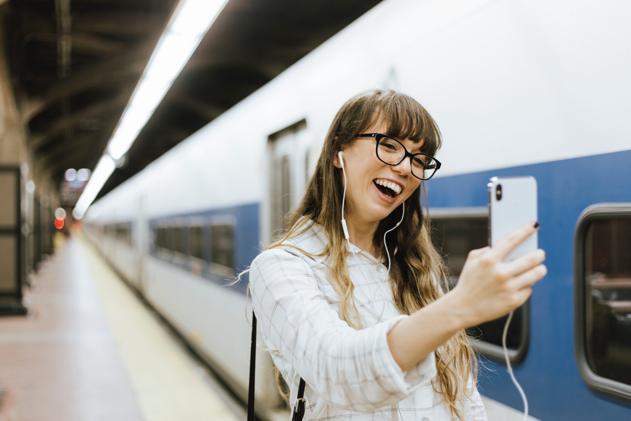 Femme souriante prenant un selfie en gare
