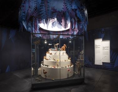 Vitrine muséale avec sculptures sous feuillage suspendu