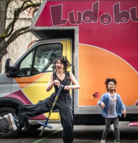 Femme et enfant jouant devant camion Ludobus coloré