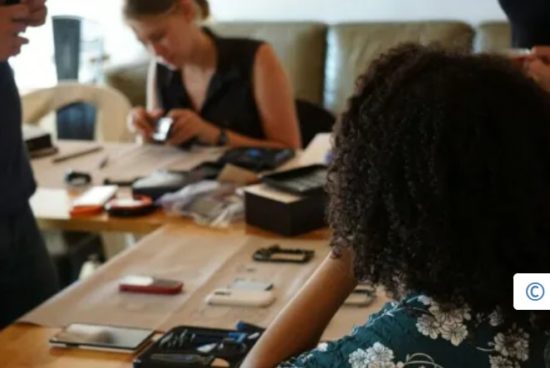Personnes réparant des smartphones autour d’une table