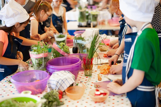 Enfants cuisinant légumes avec toques et tabliers