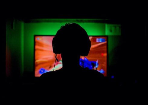 Silhouette avec casque devant écran de jeu