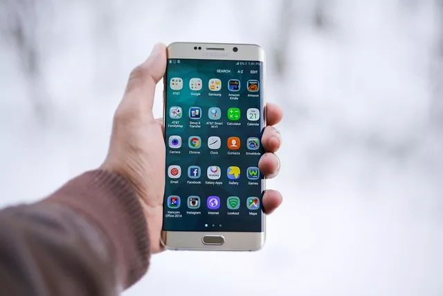 Main tenant un smartphone affichant des applications